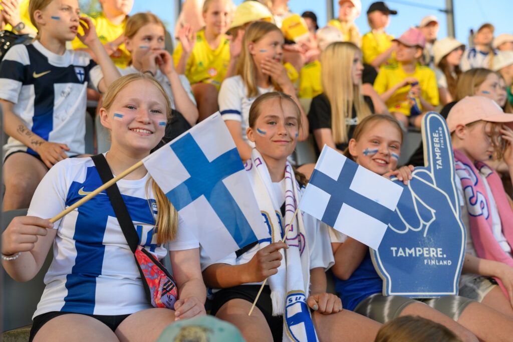 Yleisöä katsomossa Suomen liput kädessään.