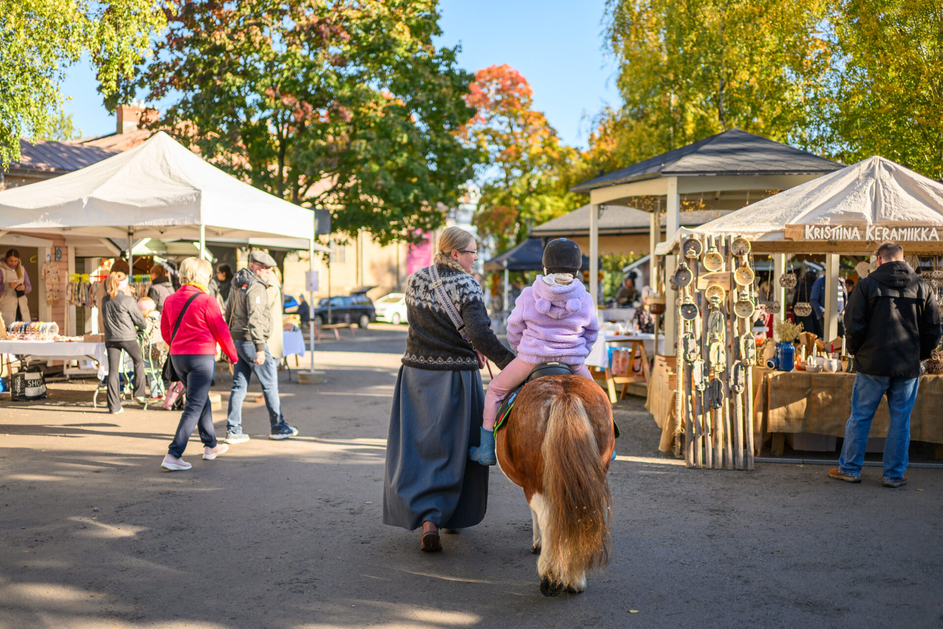 A child riding a pony in a park event.