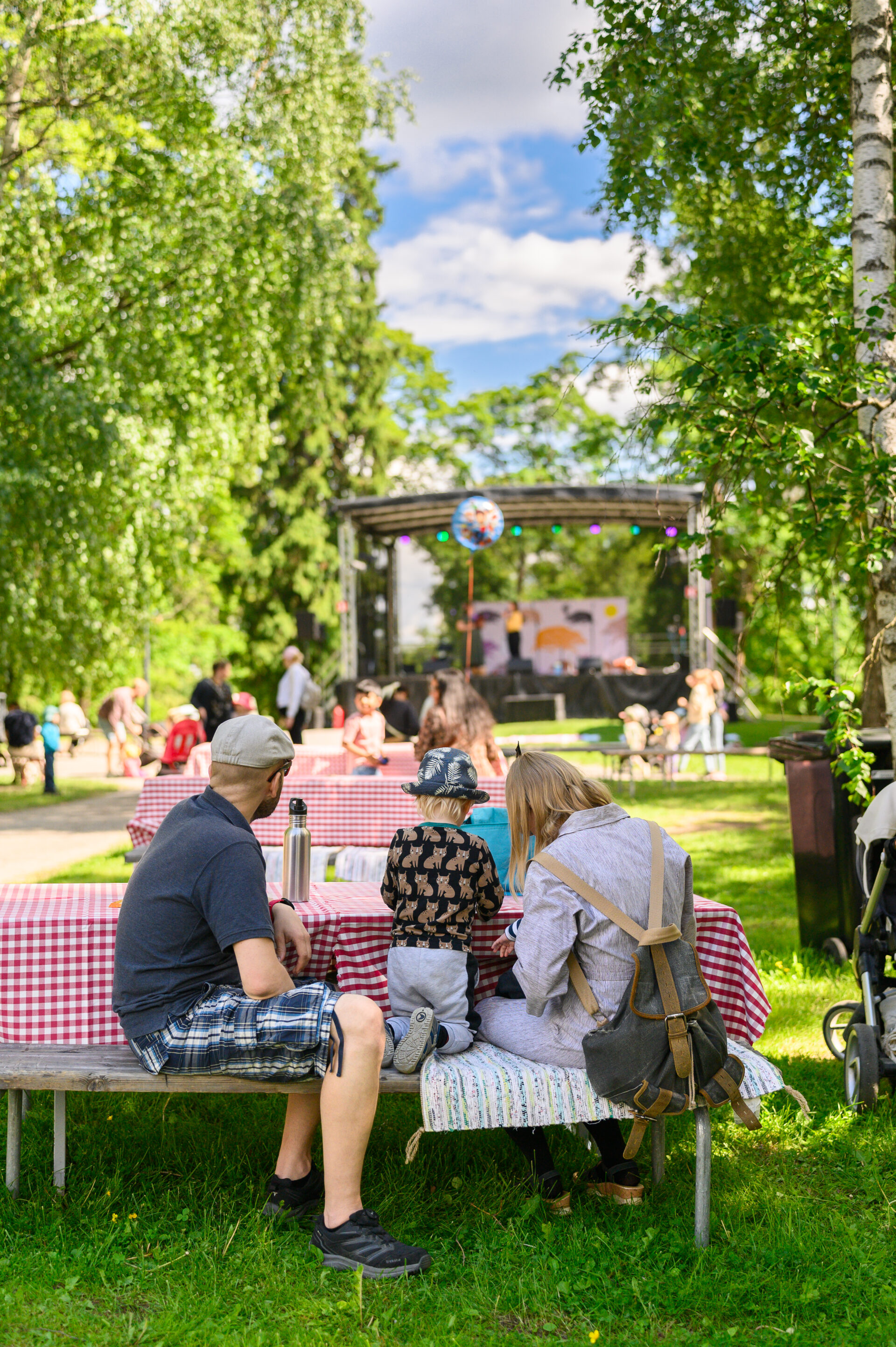 Lapsiperhe katselemassa kohti esiintymislavaa Tiitiäisen satupuistossa.