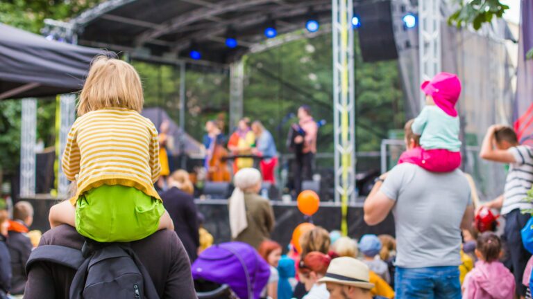 Lapsia aikuisen olkapäillä tapahtumayleisössä.