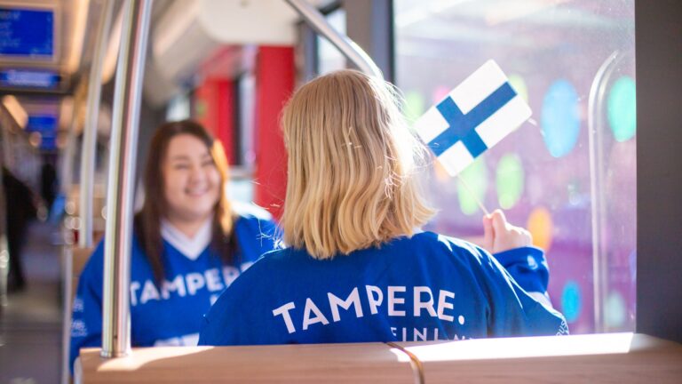 Matkustajia ratikassa Tampere-paidat päällä.